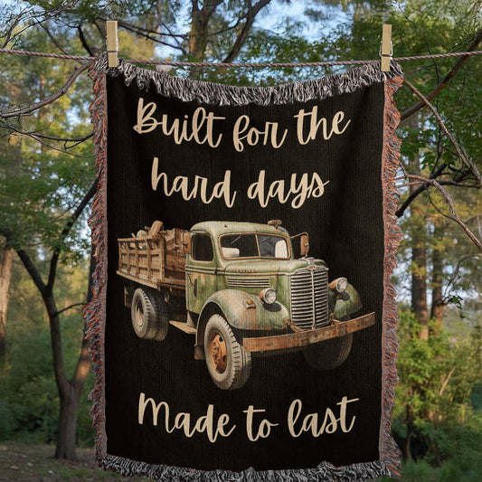 Blanket with vintage truck design and text 'Built for the hard days, Made to last' against a forest background.